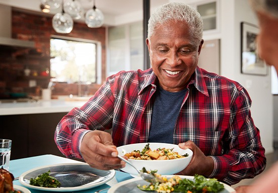Man smiling while serving food in kitchen