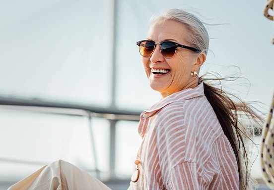Woman with sunglasses smiling while sitting on boat