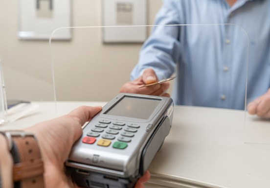 A man paying the cost of dental implants