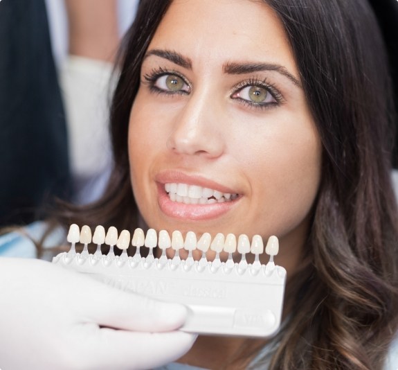 Dentist holding row of veneers in front of smiling patient