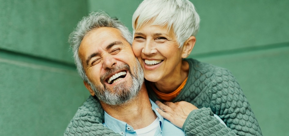 Older man and woman smiling with dental implants in Jackson