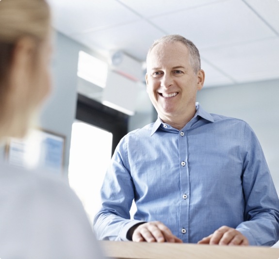 Man smiling at dental office receptionist