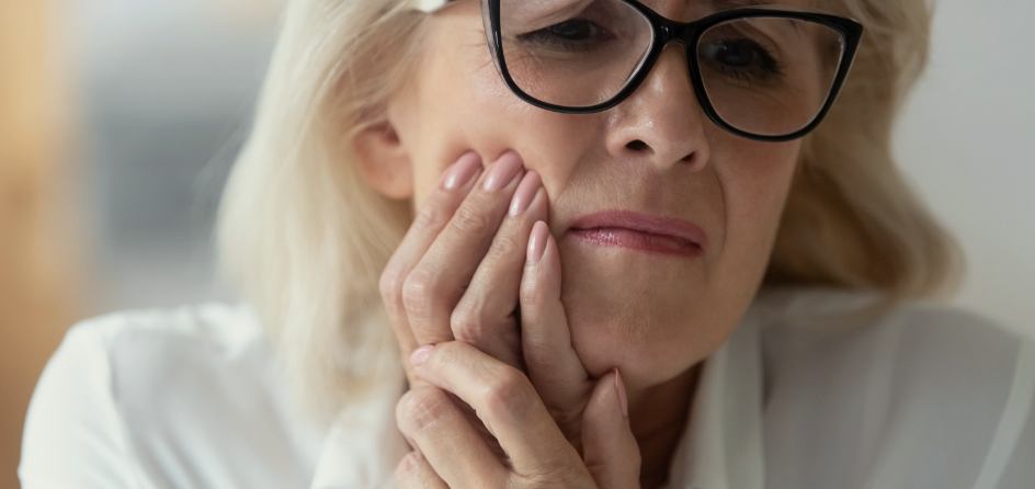 Woman holding her jaw in pain needing emergency dentist in Jackson