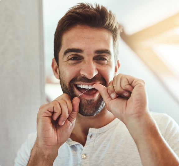 Man smiling while flossing his teeth