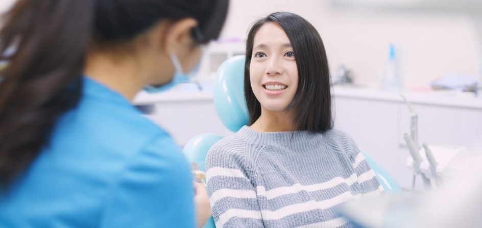 Woman in dental chair talking to dental team member