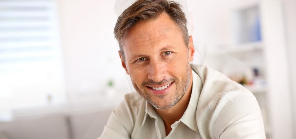 Man in white shirt smiling after gum disease treatment in Jackson