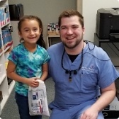 Doctor Malley smiling with young girl dental patient