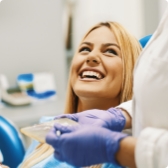Woman in dental chair grinning at her dentist