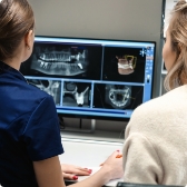 Two people looking at dental x rays on computer screen