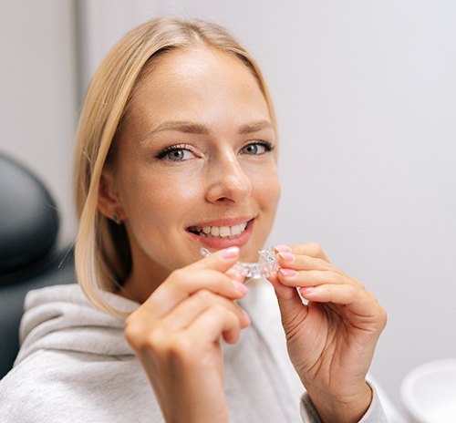 Close up of a woman smiling while holding a clear aligner