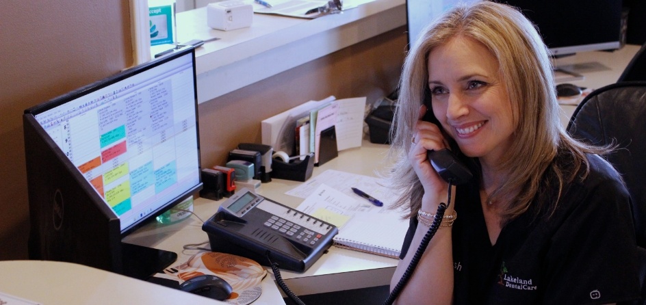 Jackson dental team member talking on the phone at front desk