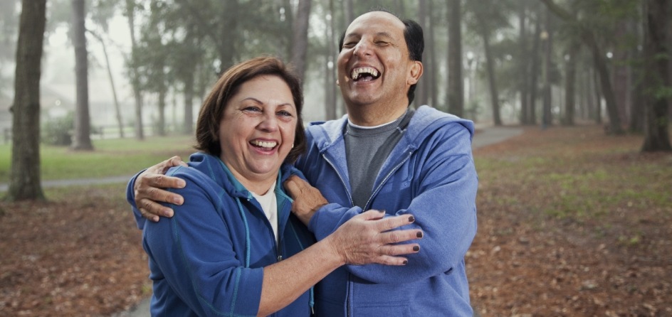 Man and woman laughing and hugging in forest