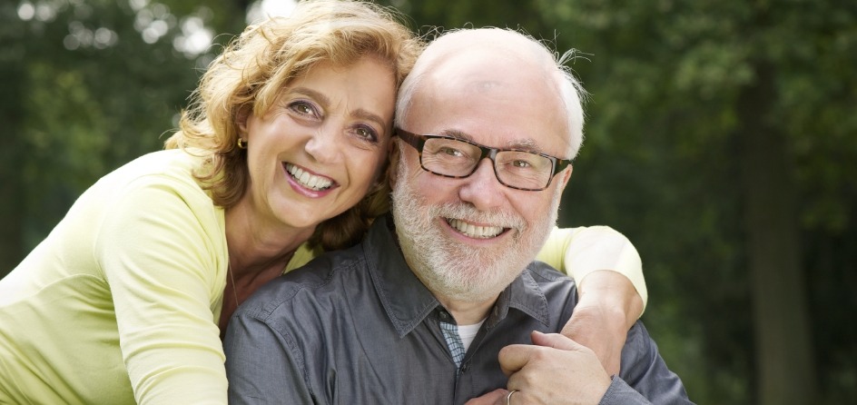 Man and woman hugging outdoors after replacing missing teeth in Jackson