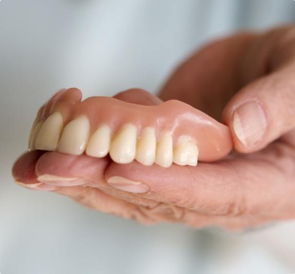 Hand holding a full upper denture