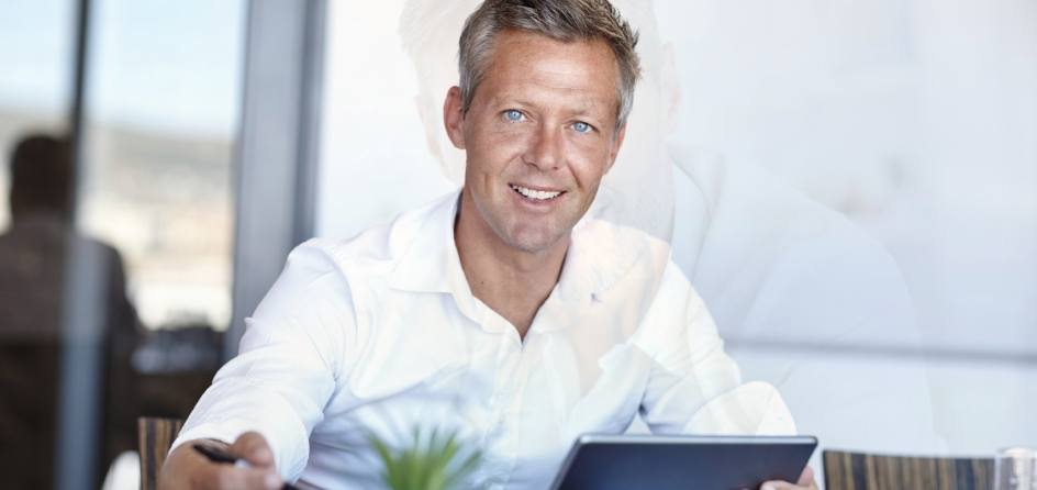 Smiling man sitting at desk with tablet