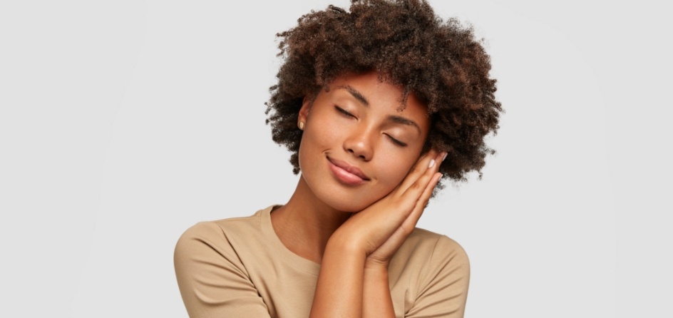 Woman making pillow shape with her hands and miming sleeping