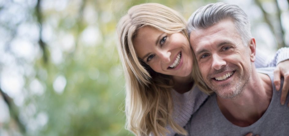 Smiling man and woman hugging outdoors