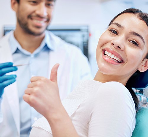 Smiling woman giving thumbs up in dentist chair