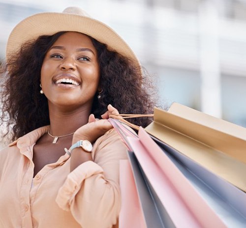 Woman smiling and carrying several shopping bags over her shoulder