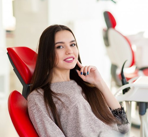 Woman tapping her chin and smiling in the patient’s chair